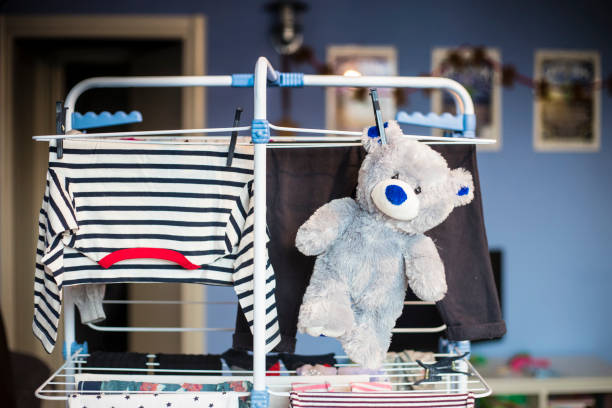 teddy bear hanging on dryer with clothes. stock photo