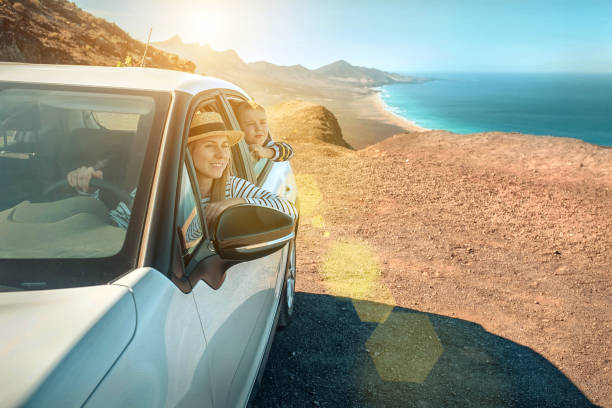 felicità madre e figlio, seduti in auto bianca e guardare la splendida vista sulla costa dell'oceano. concetto di libertà, famiglia, viaggio, viaggio, unione. - road landscape journey road trip foto e immagini stock