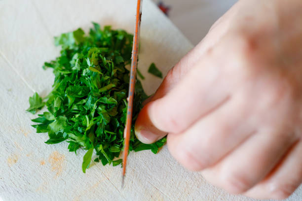 A woman shreds parsley on a wooden cutting board in the kitchen