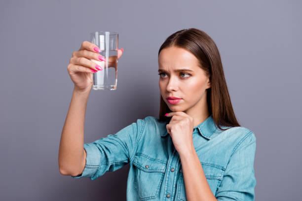 Close up portrait of not sure in quality of water she her woman Close up portrait of not sure in quality of water she her woman girl wearing casual jeans shirt outfit clothes isolated on grey background skeptical look stock pictures, royalty-free photos & images