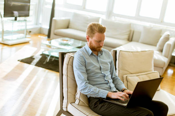 istock Man working on his laptop at home as he relaxes on a comfortable sofa 1124417138