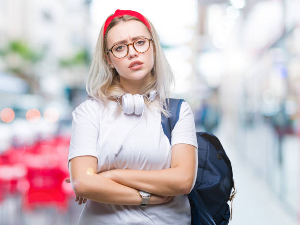 молодая блондинка-студентка в очках и рюкзаке на изолированном фоне скептически и нервно, неодобрительное выражение лица со скрещенными р� - arms crossed audio стоковые фото и изображения