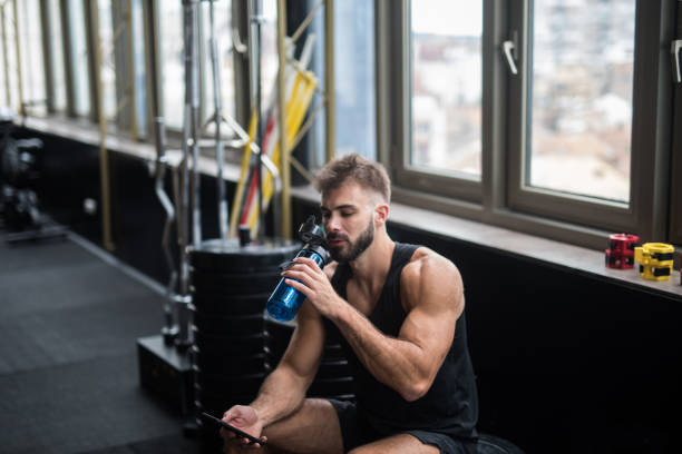 istock Young man drinking water in a gym 1124418255