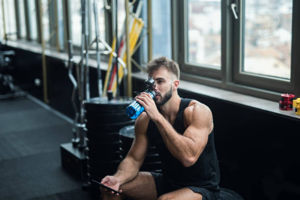 istock Young man drinking water in a gym 1124418334