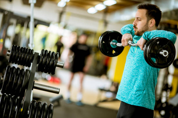 istock Handsome young man uses dumbbells in gym 1124418526