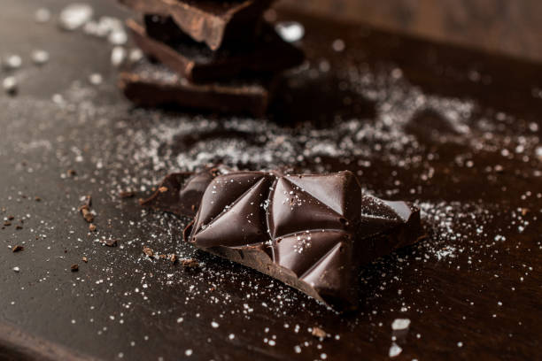 Bitter Chocolate Pieces with Sea Salt on Dark Wooden Surface.