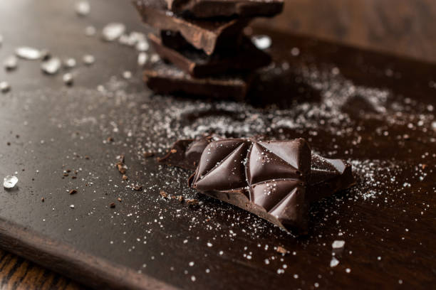 Bitter Chocolate Pieces with Sea Salt on Dark Wooden Surface.