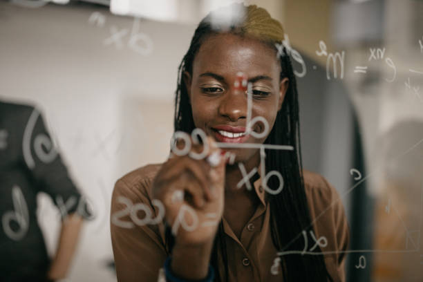 istock Smiling black woman writing MATHS Formulas on a glass 1124420658