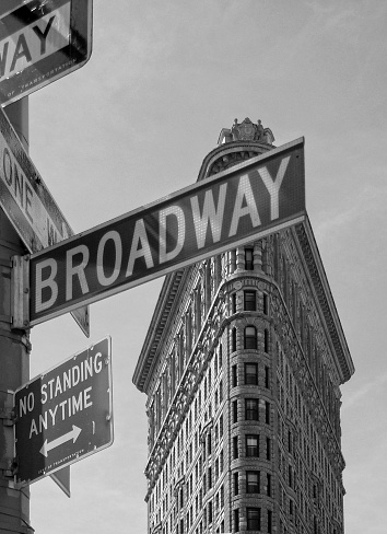 New York City, NY / USA - September 2012: The top of the Flatiron building with a Broadway sign in the foreground. Black and white.