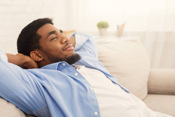 istock Handsome african-ameriacn man relaxing on sofa at home 1124421151