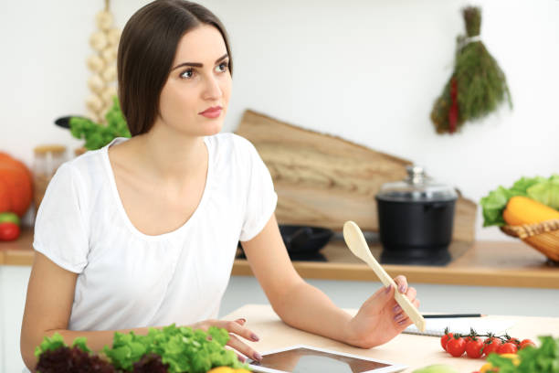 istock Beautiful Hispanic woman cooking while using tablet computer in kitchen. Housewife found new recipe for dinner or breakfast. 1124422501
