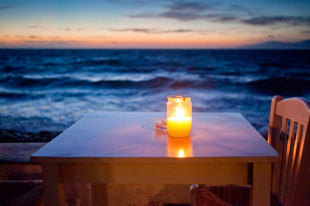 romantic table with burning candle by the sea at night