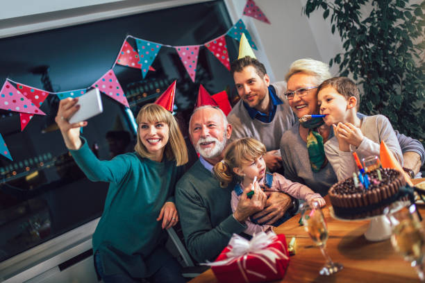 familie feiert geburtstag zusammen und machen selfie foto des großvaters. - group of people aging process home interior indoors stock-fotos und bilder