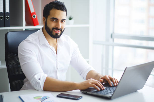 istock Young handsome entrepreneur sitting at desk and using laptop in office. 1124427251