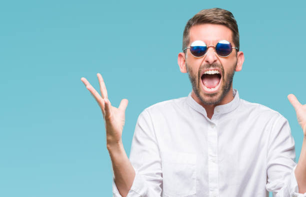 istock Young handsome man wearing glasses over isolated background celebrating mad and crazy for success with arms raised and closed eyes screaming excited. Winner concept 1124428751