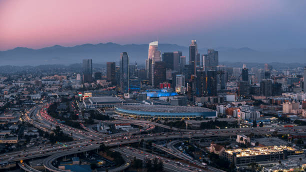 View of modern crowded cityscape Aerial view of crowded cityscape with modern skyline and traffic moving on elevated road at sunset, Los Angeles, California, USA. los angeles aerial stock pictures, royalty-free photos & images