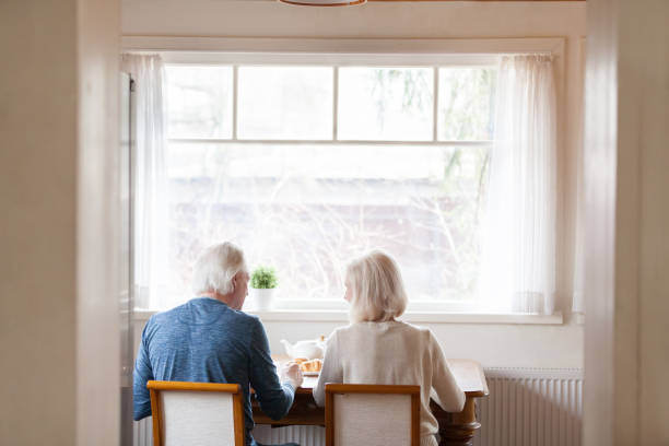 istock Rear view spouses sitting on chairs at dining table 1124436443