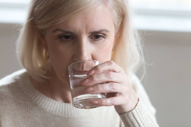 istock Close up portrait aged woman drinking still water 1124436546