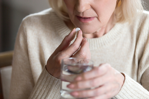 Mujer sosteniendo la píldora y el vaso de agua de cerca photo