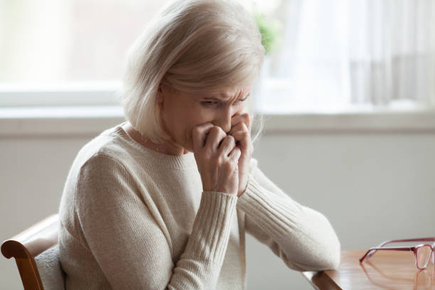 istock Middle aged woman sitting at table crying 1124436577