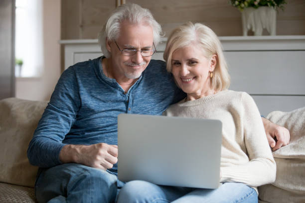 istock Aged couple sitting on couch watching movie on computer 1124436589