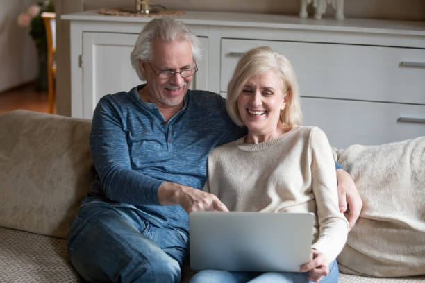 istock Senior couple sitting on comfortable couch watching video on computer 1124436594