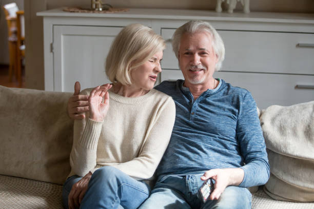 istock Middle aged attractive spouses watching tv sitting on sofa 1124436599