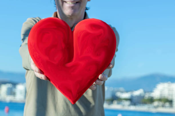 istock Faceless man holding a huge red heart in front of him 1124436683