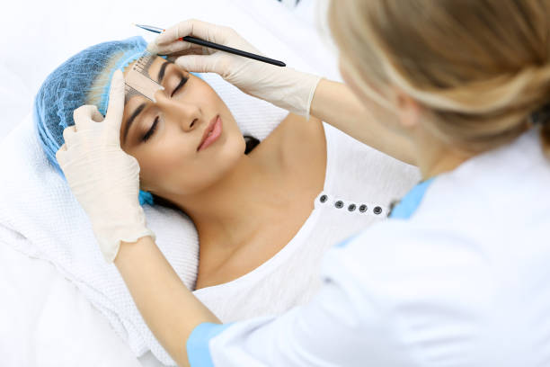 istock Professional beautician is going to correct eyebrow line at woman face using cosmetic ruler. Permanent brow makeup in beauty salon, closeup.  Cosmetology treatment. 1124438847