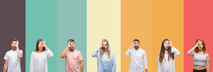 Collage of different ethnics young people over colorful stripes isolated background doing ok gesture shocked with surprised face, eye looking through fingers. Unbelieving expression.