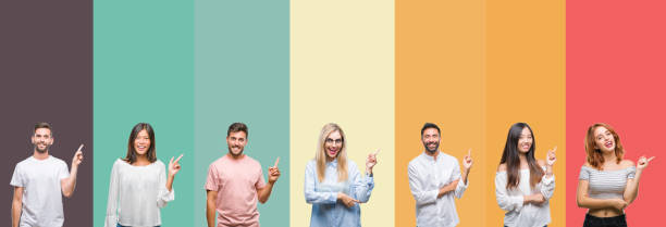 istock Collage of different ethnics young people over colorful stripes isolated background with a big smile on face, pointing with hand and finger to the side looking at the camera. 1124439749