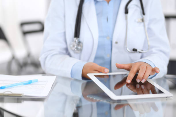 istock Close-up of female physician hands using digital tablet  while sitting at glass desk at hospital office. Medicine and healthcare concept. 1124441373