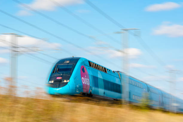 A TGV Duplex high-speed train in Ouigo livery driving at full speed in the french countryside. Varreddes, France - August 18, 2018: A TGV Duplex high-speed train in Ouigo livery from french company SNCF driving at full speed on the East European high-speed line (artist's impression). intercity train photos stock pictures, royalty-free photos & images