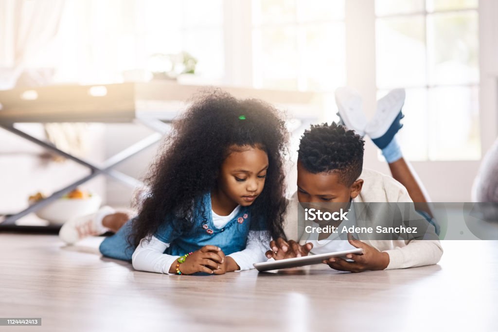 The digital world answers to their curiosity Shot of two adorable little siblings using a digital tablet together at home Child Stock Photo