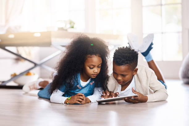The digital world answers to their curiosity Shot of two adorable little siblings using a digital tablet together at home south africa youth day stock pictures, royalty-free photos & images