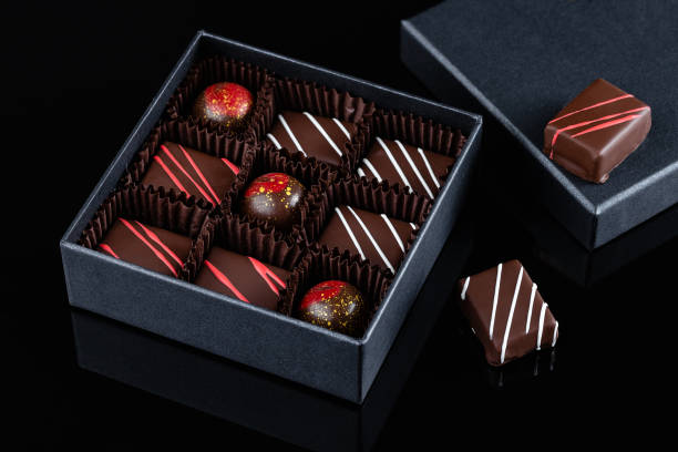 assortment of luxury bonbons with red splashes in box on black background - craft chocolate candy black box imagens e fotografias de stock