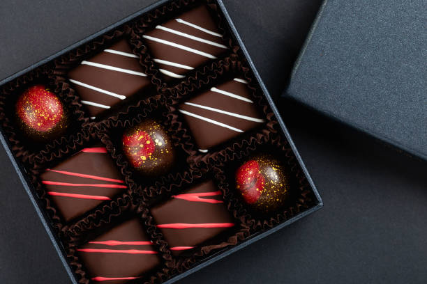 assortment of luxury bonbons with red splashes in box on black background - craft chocolate candy black box imagens e fotografias de stock