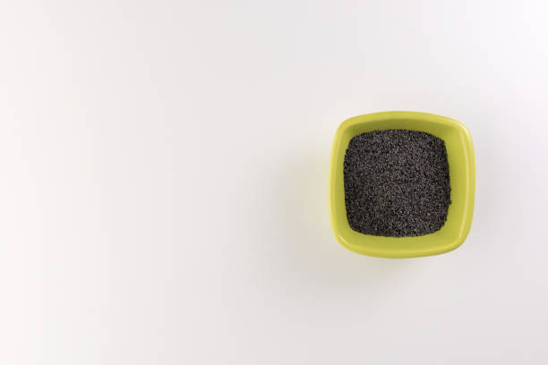 Poppy seeds in a ceramic plate isolated on wooden background. Selective focus