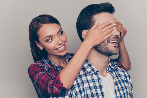 Close-up portrait of two nice lovable sweet attractive beautiful dreamy cheerful people husband wife wearing checked shirt girl closing guy's eyes isolated over gray pastel background