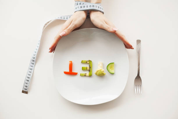 istock Diet or weight control concept. Centimeter tape and fork on a white background with a place for inserting text. concept of health, weight loss, diet, proper nutrition 1124461647
