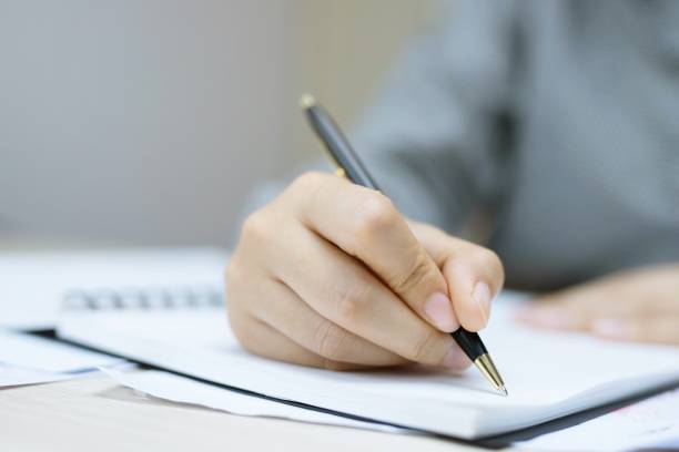 istock close up hand young man are sitting using pen writing Record Lecture notepad into the book in the office 1124463249