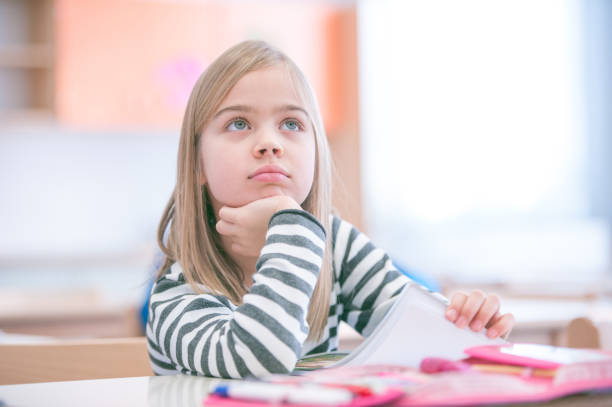 Cute Schoolgirl Sitting in School Classroom Drawing stock photo