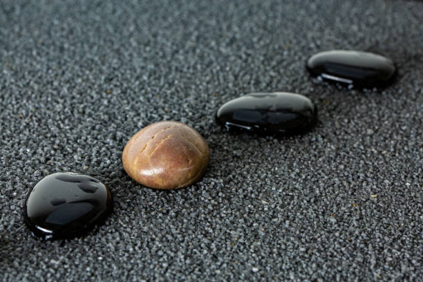 istock Black pebbles on black sand background with brown pebble. 1124475057