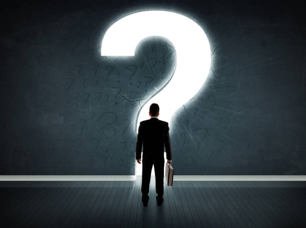 istock Business man looking at wall with a bright question mark 1124475303