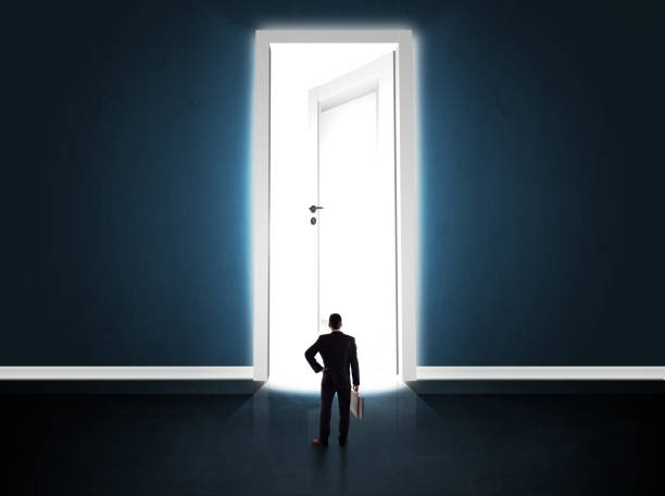 istock Business man looking at big bright opened door 1124475360