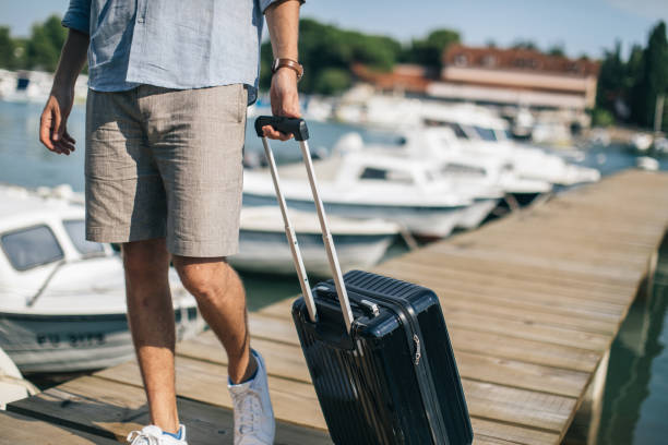 istock Tourist man walking on pier with suitcase 1124476682
