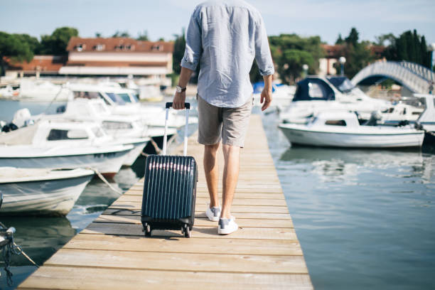 istock Tourist man walking on pier with suitcase 1124477227