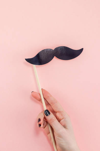 istock Woman hands with black paper moustaches 1124479074