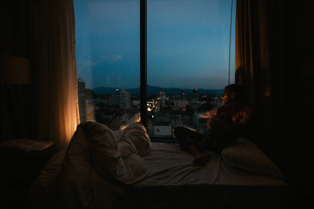 istock Guy sitting by the window at night alone 1124485296