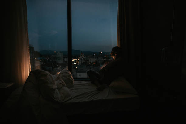 istock Man sitting by the window at night alone 1124485381